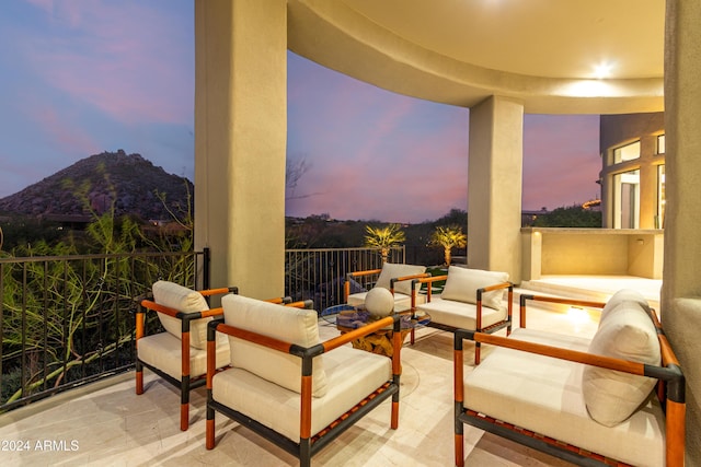 patio terrace at dusk featuring a mountain view and a balcony