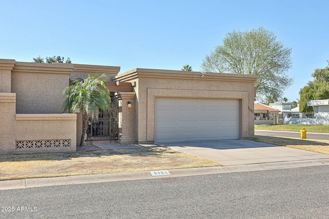 view of front of house with driveway, a garage, a fenced front yard, a gate, and stucco siding