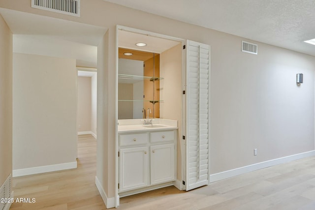 hallway featuring light hardwood / wood-style flooring, sink, and a textured ceiling