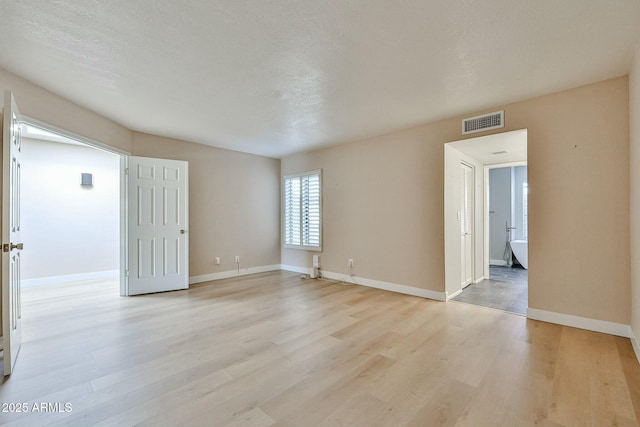 unfurnished room with a textured ceiling and light hardwood / wood-style flooring