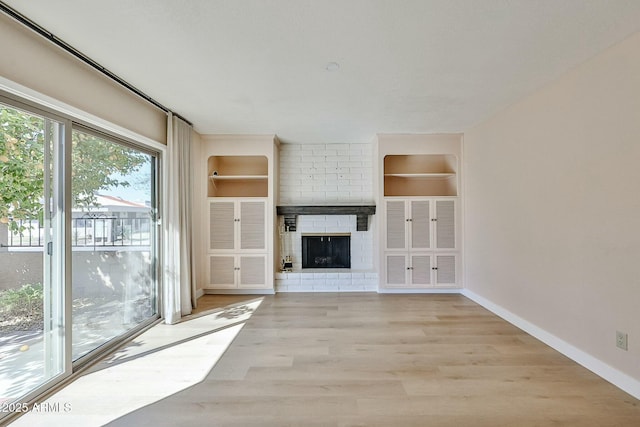 unfurnished living room featuring a brick fireplace, light hardwood / wood-style flooring, and built in features