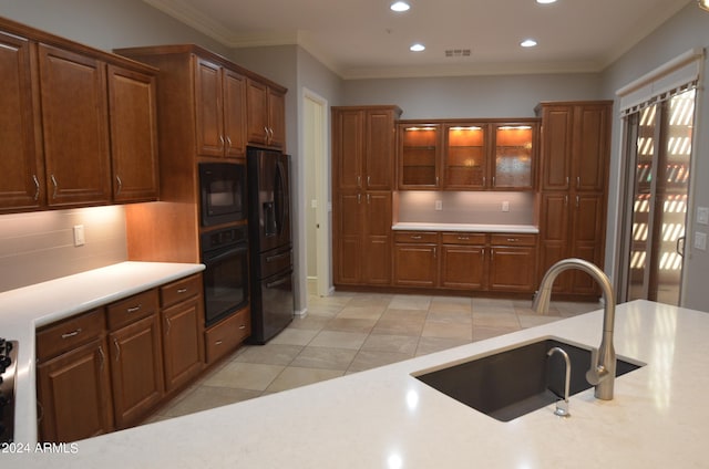 kitchen with light countertops, visible vents, glass insert cabinets, a sink, and black appliances