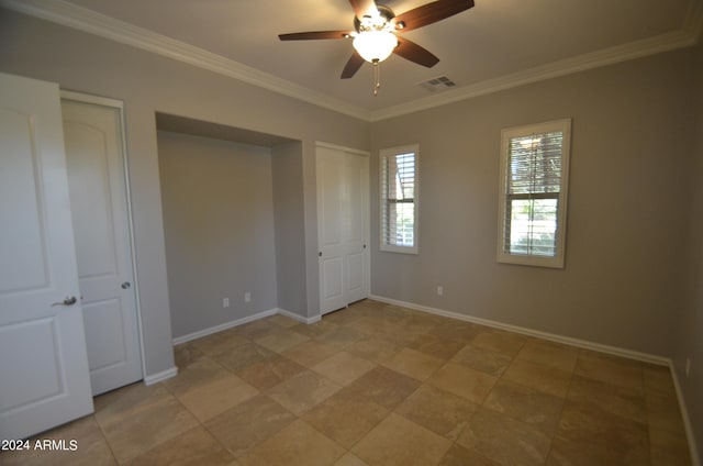 unfurnished bedroom featuring multiple closets, visible vents, crown molding, and baseboards