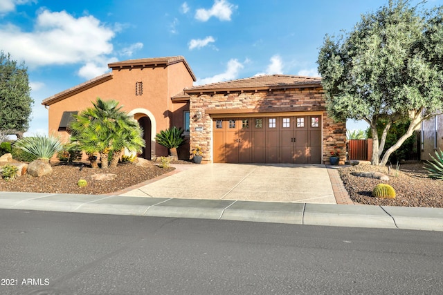 mediterranean / spanish-style house with stucco siding, an attached garage, fence, stone siding, and driveway