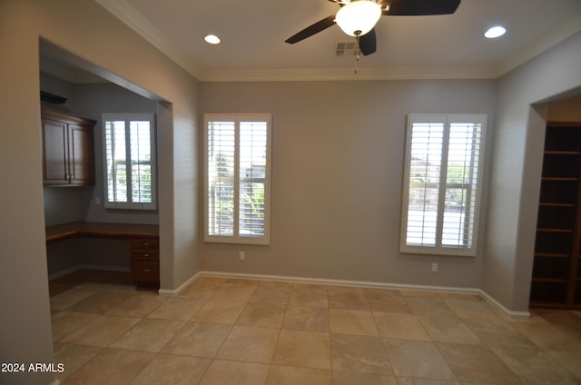 empty room with baseboards, crown molding, visible vents, and built in desk