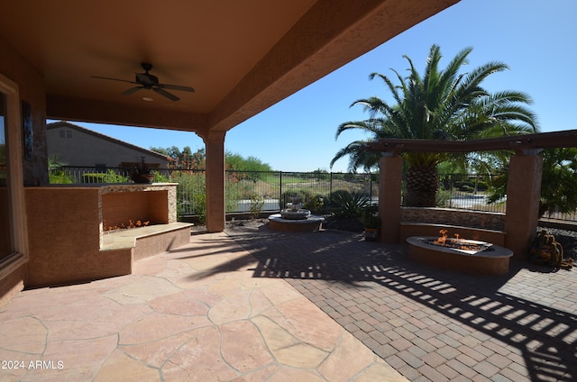 view of patio featuring a ceiling fan, fence, and a fire pit