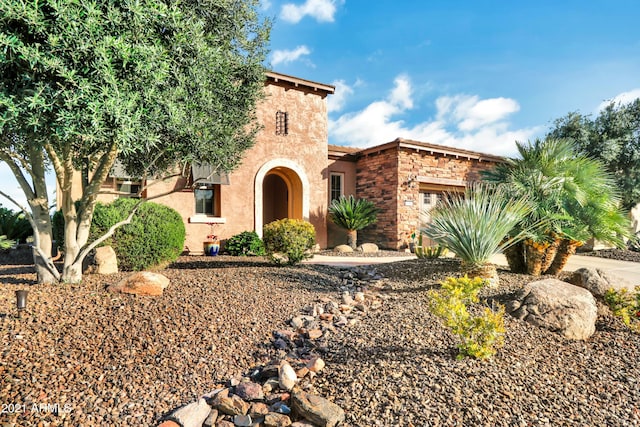 view of front of property featuring a garage, stone siding, and stucco siding