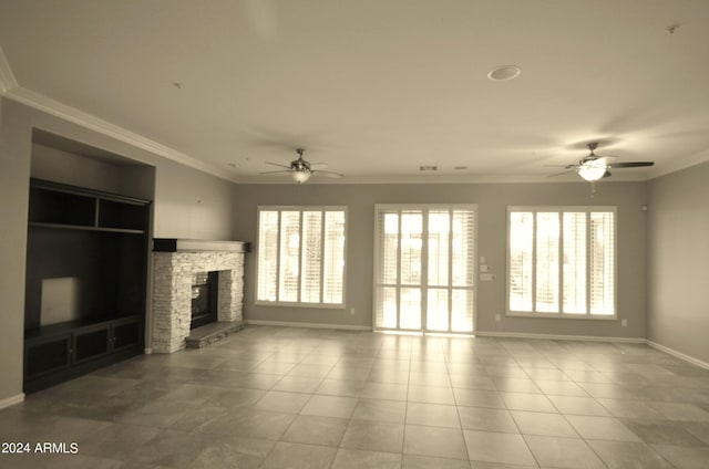 unfurnished living room with crown molding, a stone fireplace, baseboards, and tile patterned floors