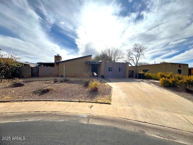 view of front of property featuring driveway, fence, and stucco siding