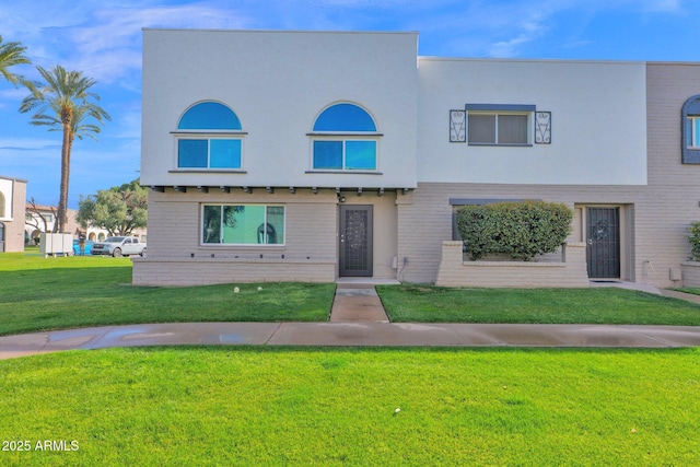 townhome / multi-family property with a front lawn and stucco siding