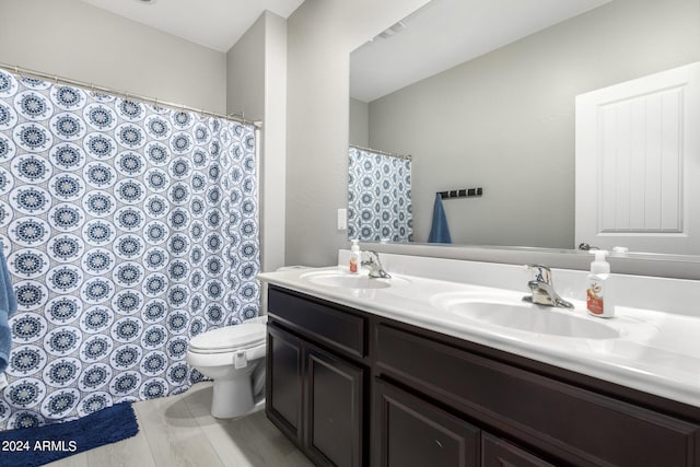 bathroom featuring dual bowl vanity and toilet