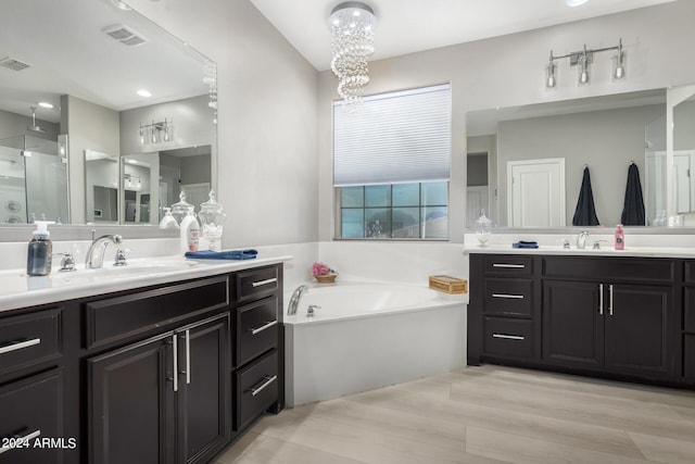 bathroom featuring double vanity, wood-type flooring, a washtub, and an inviting chandelier