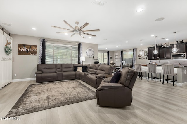 living room featuring sink, ceiling fan, and light hardwood / wood-style floors