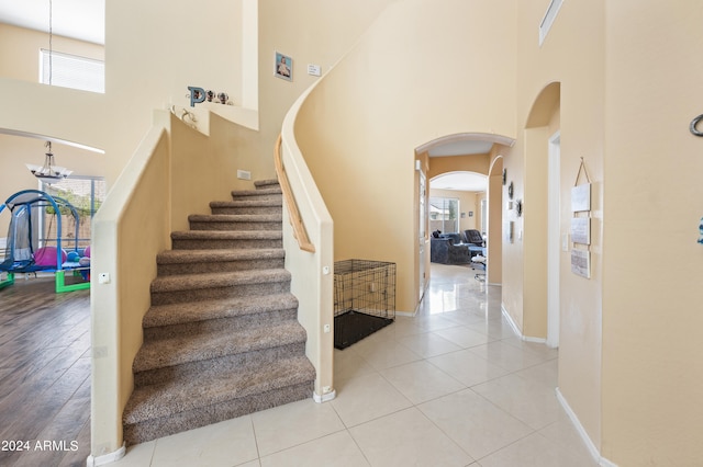 staircase featuring wood-type flooring and a towering ceiling