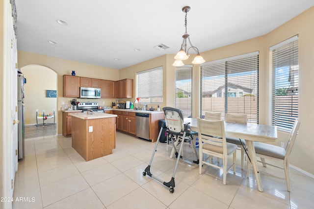 kitchen featuring pendant lighting, a kitchen island, stainless steel appliances, and a healthy amount of sunlight