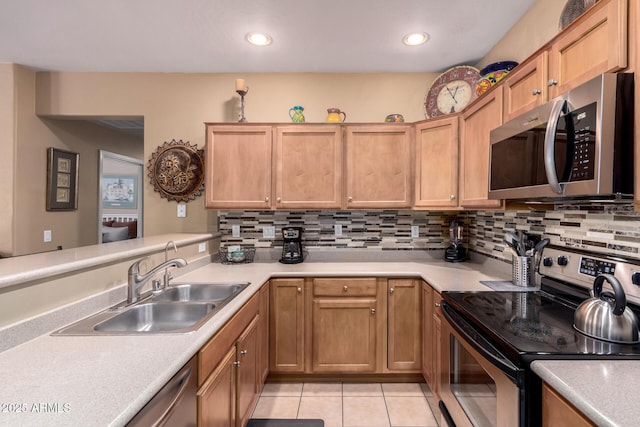 kitchen featuring tasteful backsplash, appliances with stainless steel finishes, light countertops, and a sink