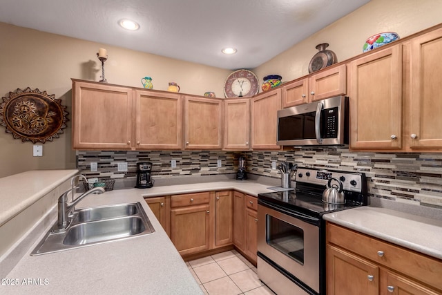 kitchen with backsplash, stainless steel appliances, light countertops, and a sink