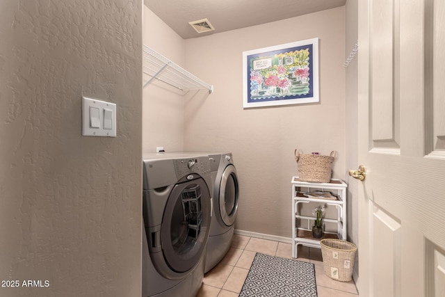 laundry room with visible vents, baseboards, washing machine and dryer, light tile patterned floors, and laundry area