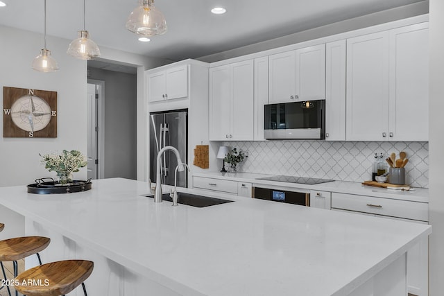 kitchen featuring appliances with stainless steel finishes, tasteful backsplash, a breakfast bar, sink, and pendant lighting