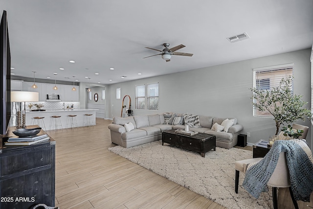 living room with ceiling fan, sink, and light hardwood / wood-style flooring