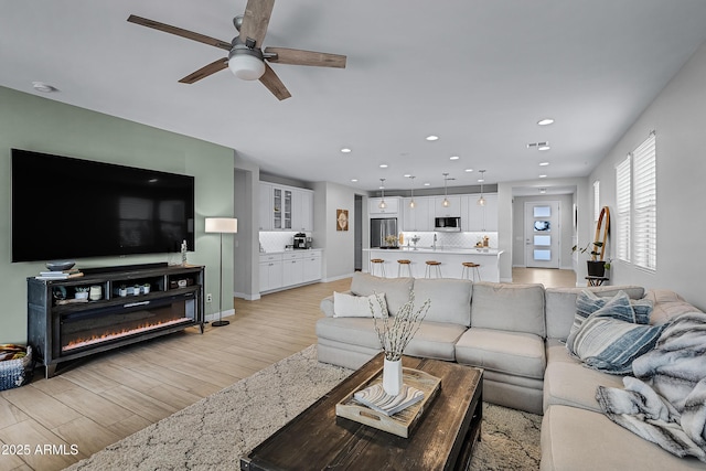 living room with ceiling fan and light hardwood / wood-style floors