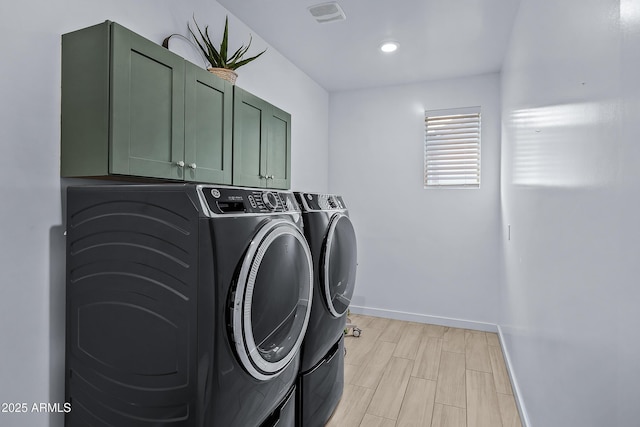 washroom with cabinets, light hardwood / wood-style flooring, and washer and clothes dryer