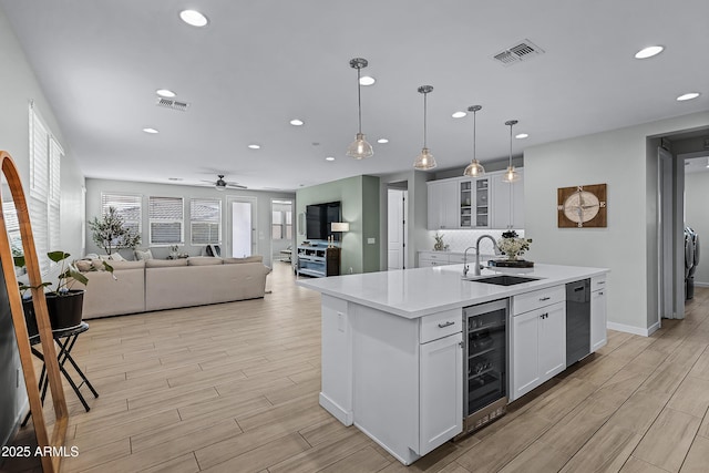 kitchen with white cabinetry, sink, wine cooler, pendant lighting, and a kitchen island with sink