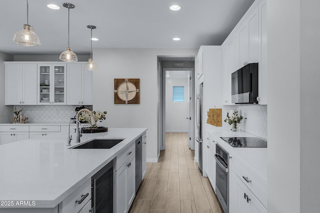 kitchen with black appliances, white cabinetry, sink, and beverage cooler