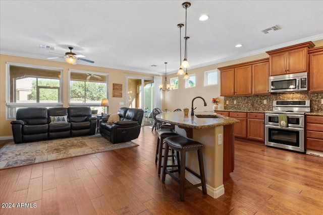 856 E Harmony Way, San Tan Valley, AZ 85140 - kitchen with stainless steel appliances, a sink, open floor plan, brown cabinets, and ornamental molding