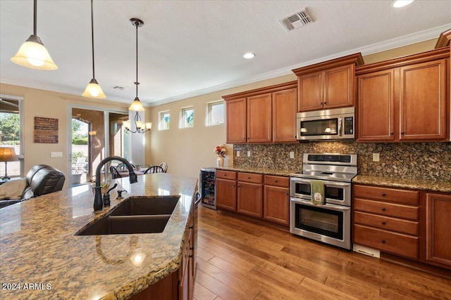 856 E Harmony Way, San Tan Valley, AZ 85140 - kitchen featuring stainless steel appliances, a sink, brown cabinetry, ornamental molding, and pendant lighting