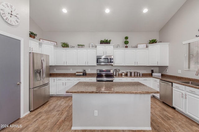 kitchen with stainless steel appliances, white cabinetry, and a center island