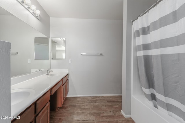 full bathroom with double vanity, baseboards, a sink, and wood finished floors