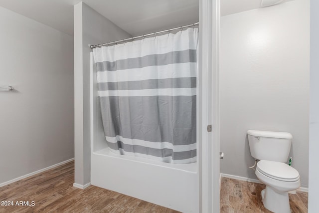 bathroom featuring shower / bath combo with shower curtain, baseboards, toilet, and wood finished floors