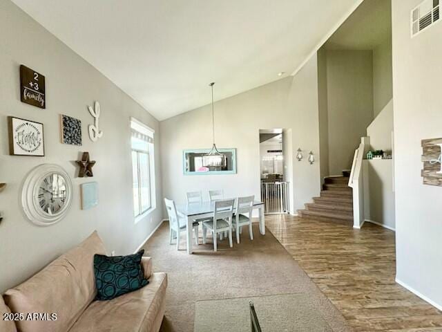 dining room featuring visible vents, wood finished floors, high vaulted ceiling, baseboards, and stairs