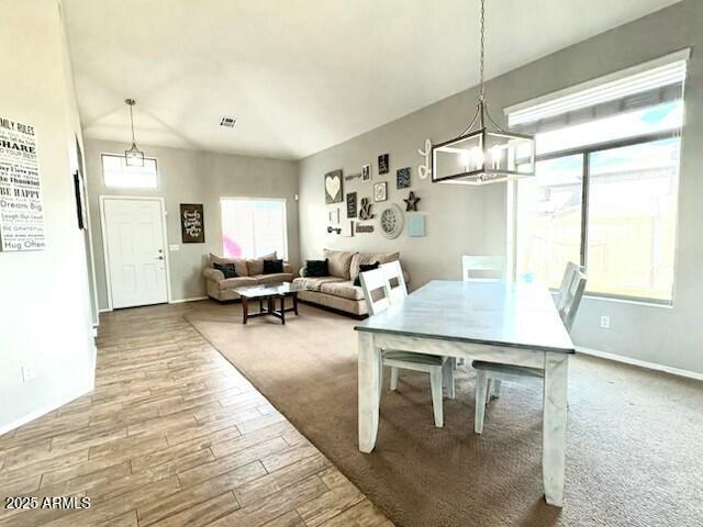 dining space featuring baseboards, visible vents, an inviting chandelier, and wood finished floors