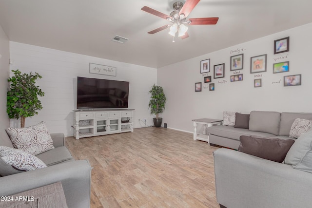 living room featuring light wood finished floors, visible vents, and a ceiling fan