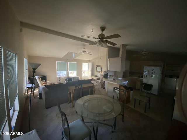 carpeted dining space with ceiling fan and vaulted ceiling