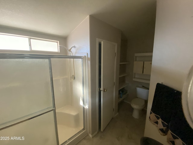 bathroom featuring toilet and a shower with door