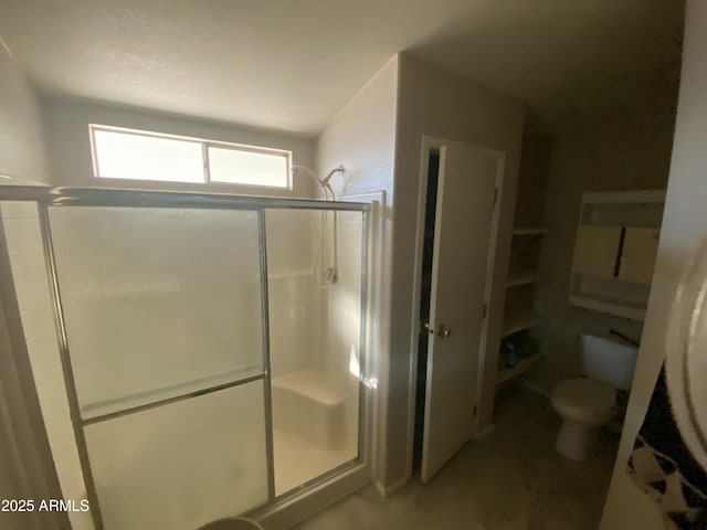 bathroom featuring toilet and a shower with door