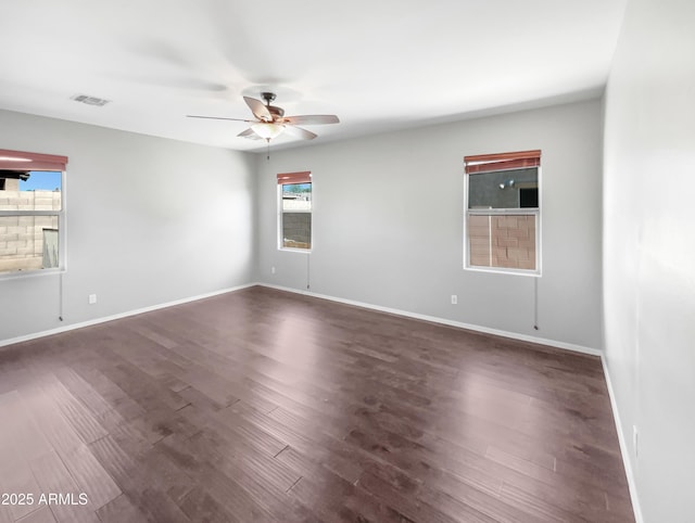 empty room with visible vents, baseboards, dark wood finished floors, and a ceiling fan