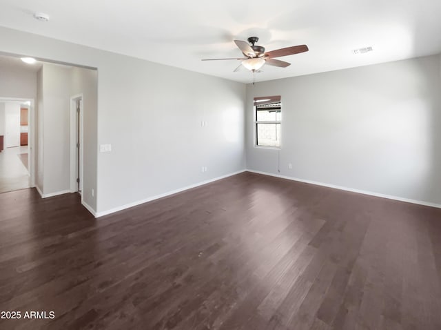 spare room with dark wood-style floors, baseboards, visible vents, and a ceiling fan