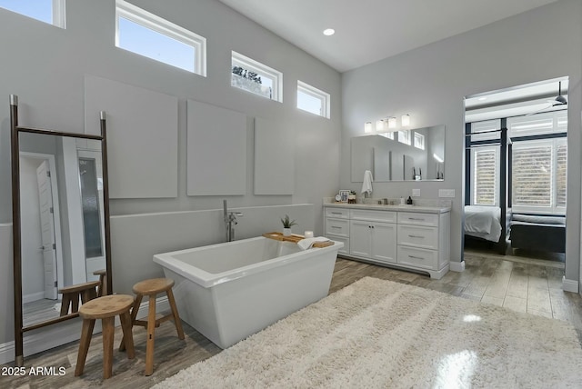 bathroom with a washtub, hardwood / wood-style floors, and vanity