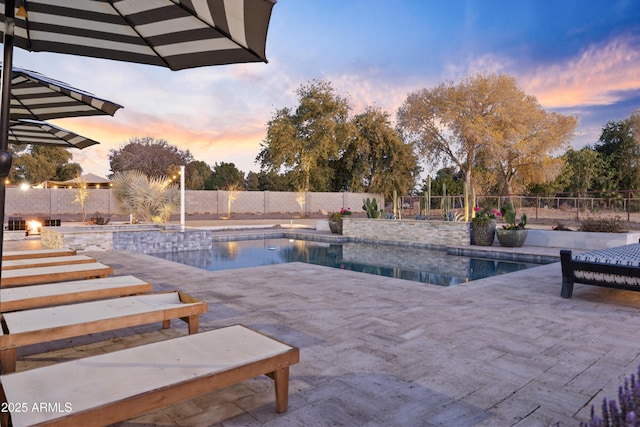 pool at dusk featuring a patio