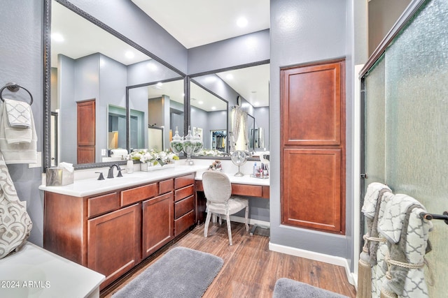 bathroom with wood-type flooring, a shower with shower door, and vanity