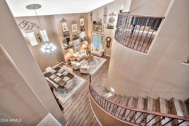 stairs with an inviting chandelier, vaulted ceiling, and wood-type flooring