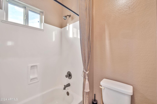 bathroom with shower / bath combination with curtain and toilet