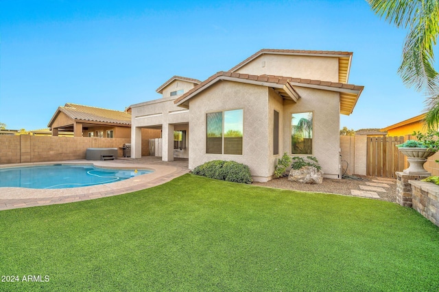 rear view of property featuring a fenced in pool, a patio, and a lawn