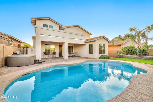 back of property with a pool with hot tub and a patio