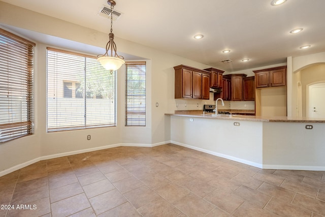 kitchen featuring hanging light fixtures, light tile patterned flooring, sink, and light stone counters