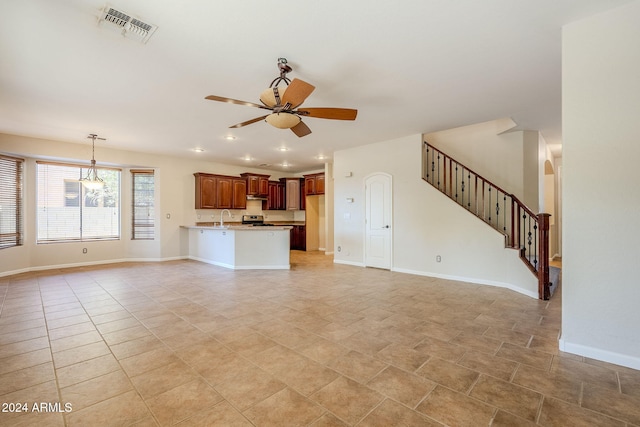 unfurnished living room featuring light tile patterned floors, ceiling fan with notable chandelier, and sink